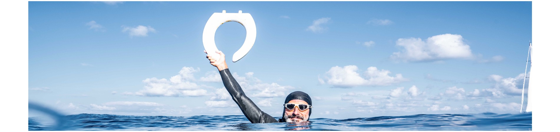 man in diving gear in the ocean holding up a toilet seat